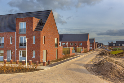 residential neighborhood with modern brick houses and a newly paved road construction site along the street 2 homes under development 2 story buildings