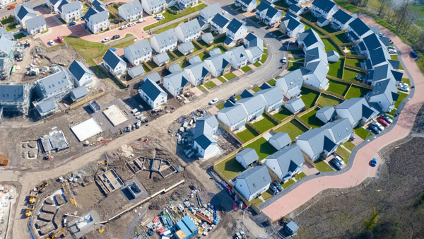 aerial view of a residential construction site featuring several new homes arranged in neighborhoods with green lawns and pathways construction progress visible 5 new homes development