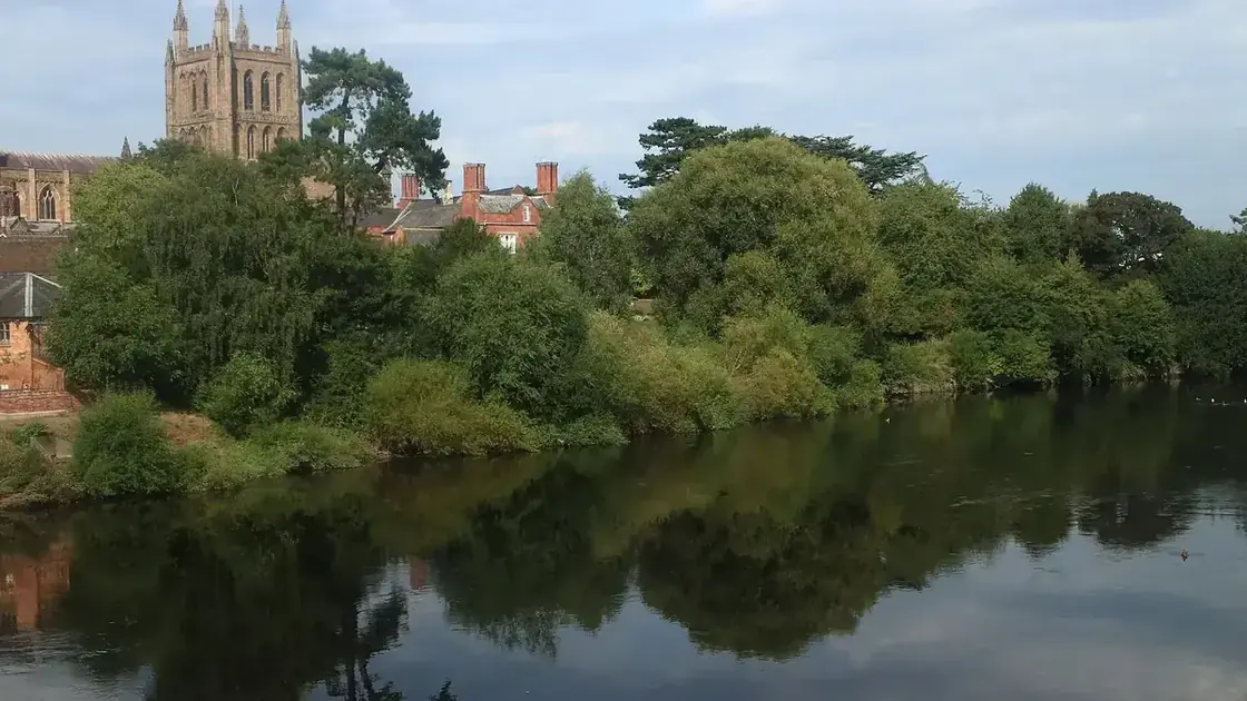 Hereford Cathedral and riverside trees reflected in the River Wye.