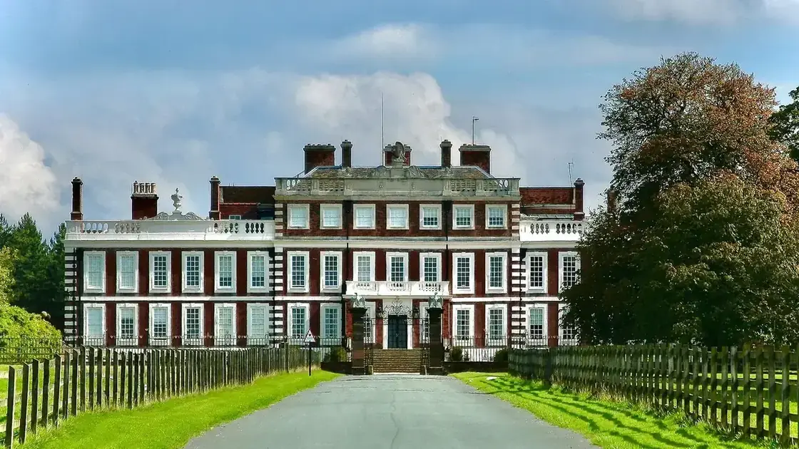 The long stone elevation of Knowsley Hall viewed across its open lawn.