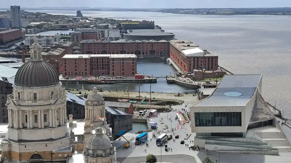 Liverpool's Pier Head waterfront and landmark buildings beneath a blue daytime sky.