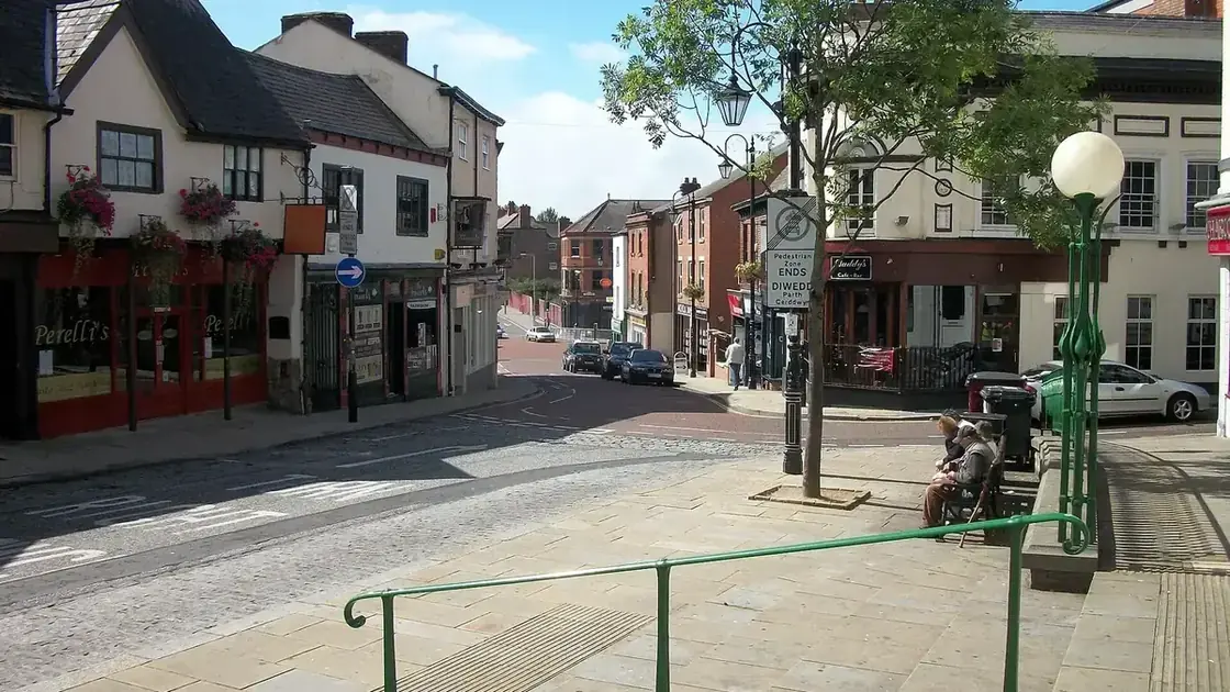 Wrexham town centre with a covered public space and St Giles' church tower beyond.